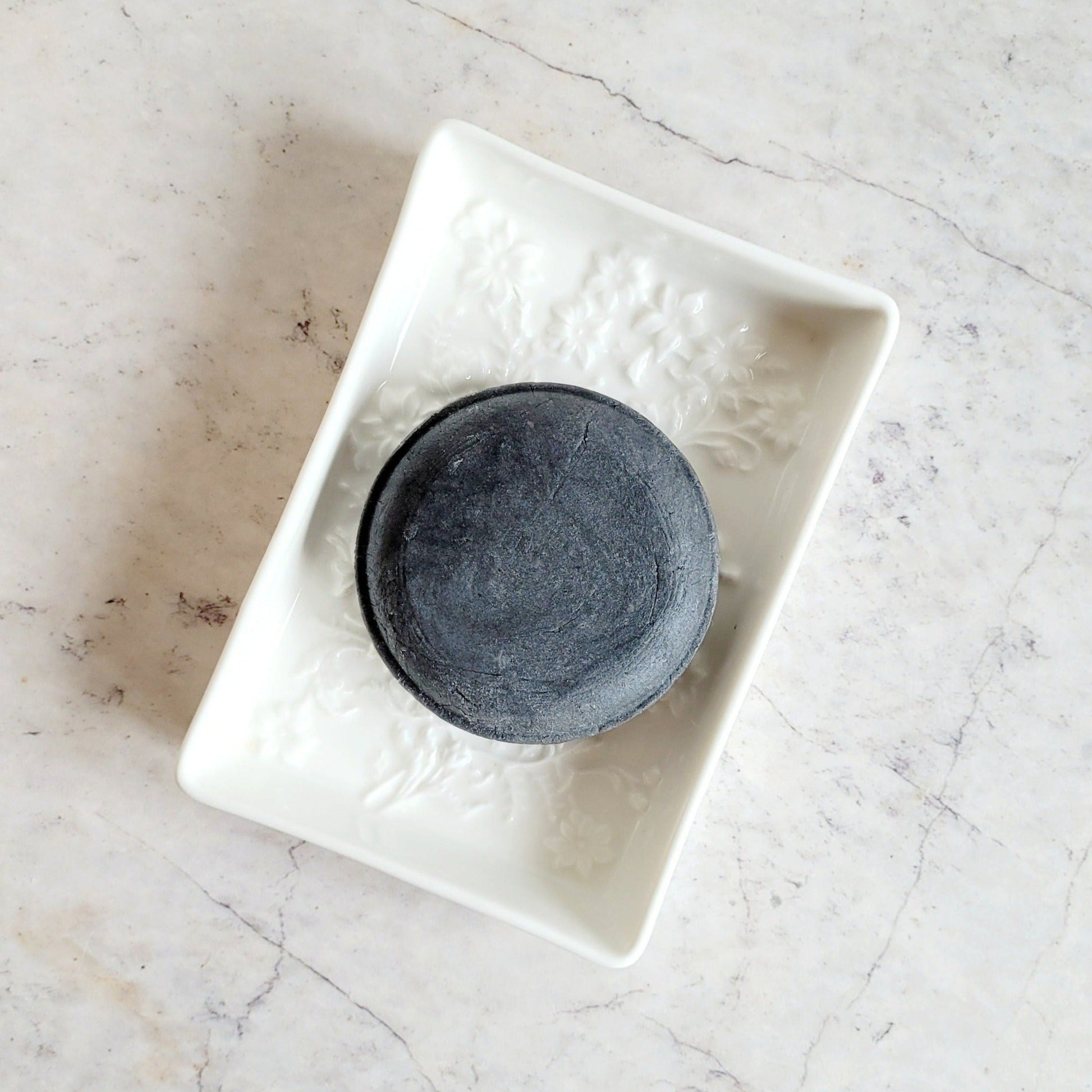 charcoal shampoo bar. round plastic free shampoo bar in ceramic soap dish.
